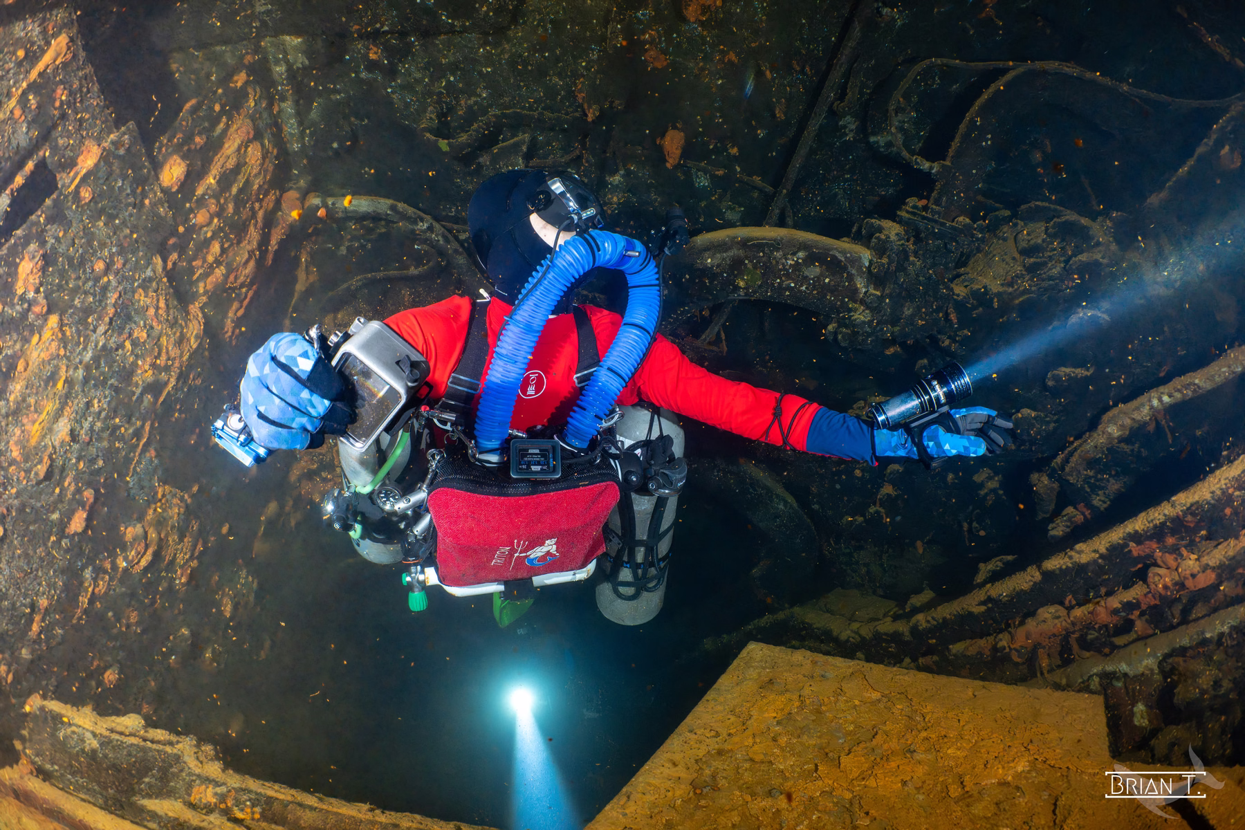 A diver in a drysuit with a torch exploring a wreck in Truk Lagoon