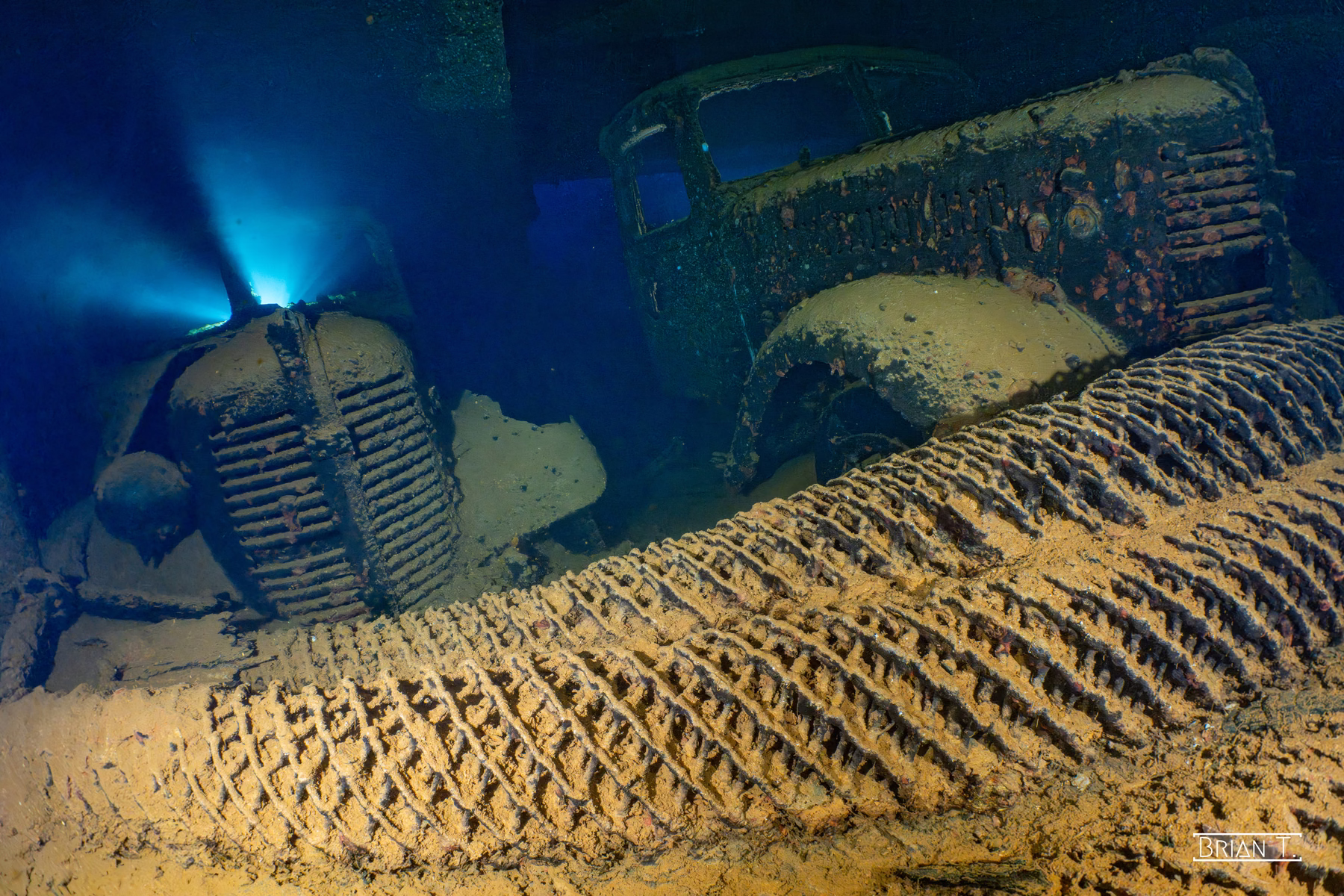 A truck inside a shipwreck cargo hold, backlit by a diver's torch