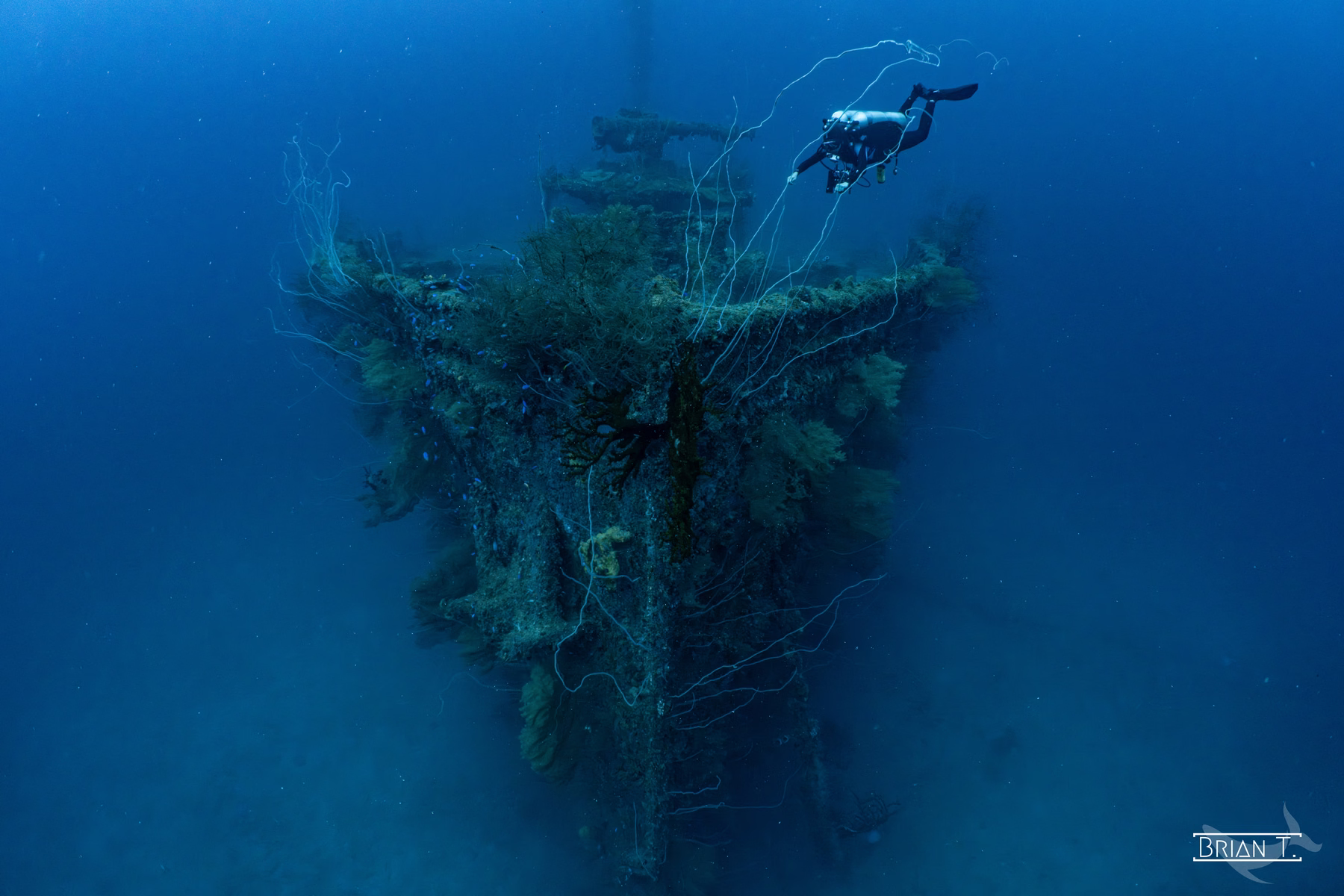 A diver hovers beside the masts of a large shipwreck in Truk Lagoon